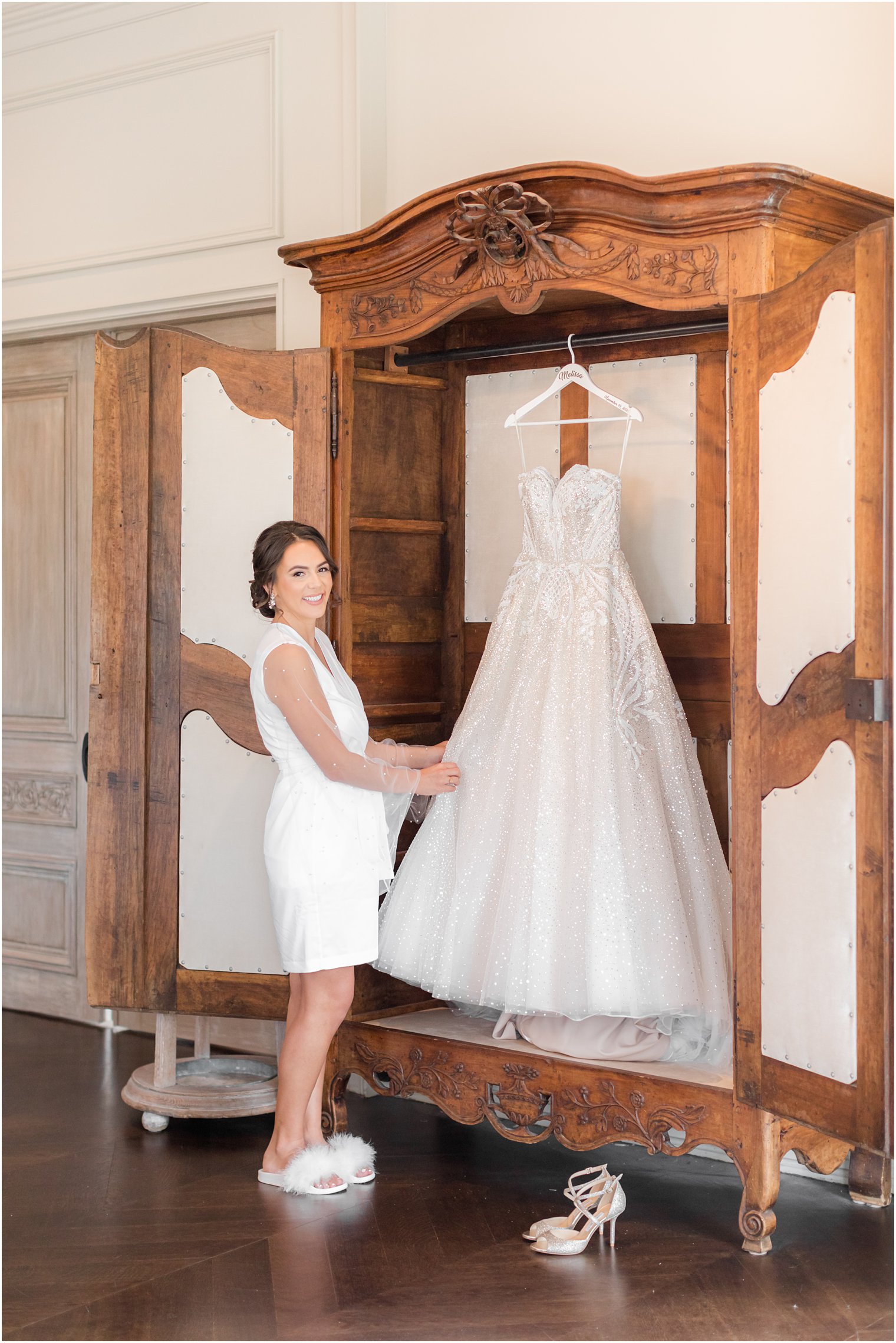 bride looks at wedding gown hanging in closet in bridal suite of Park Chateau Estate