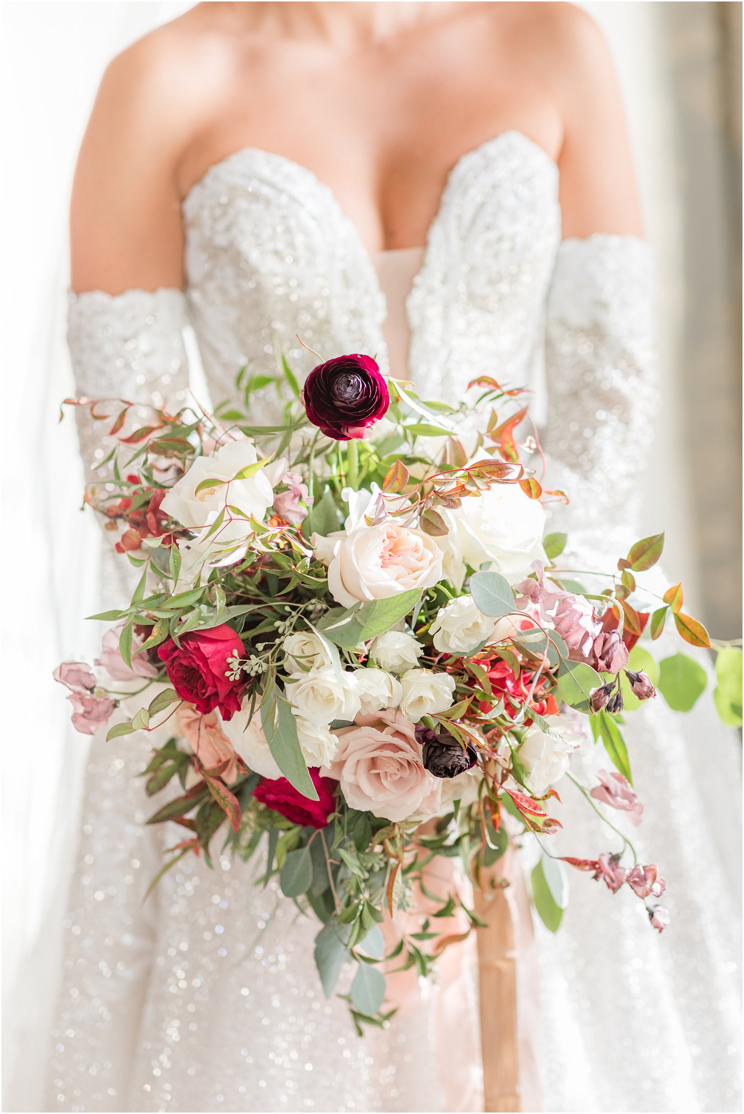 bride holds bouquet of ivory and red flowers at Park Chateau Estate