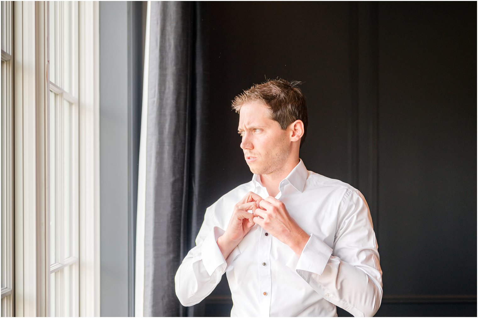 groom adjusts buttons on his shirt during prep 