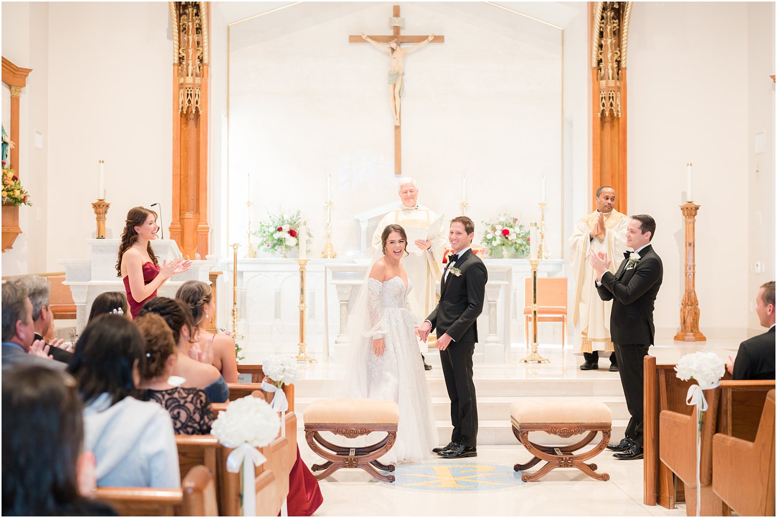 couple laughs at guests after kiss during NJ church wedding ceremony