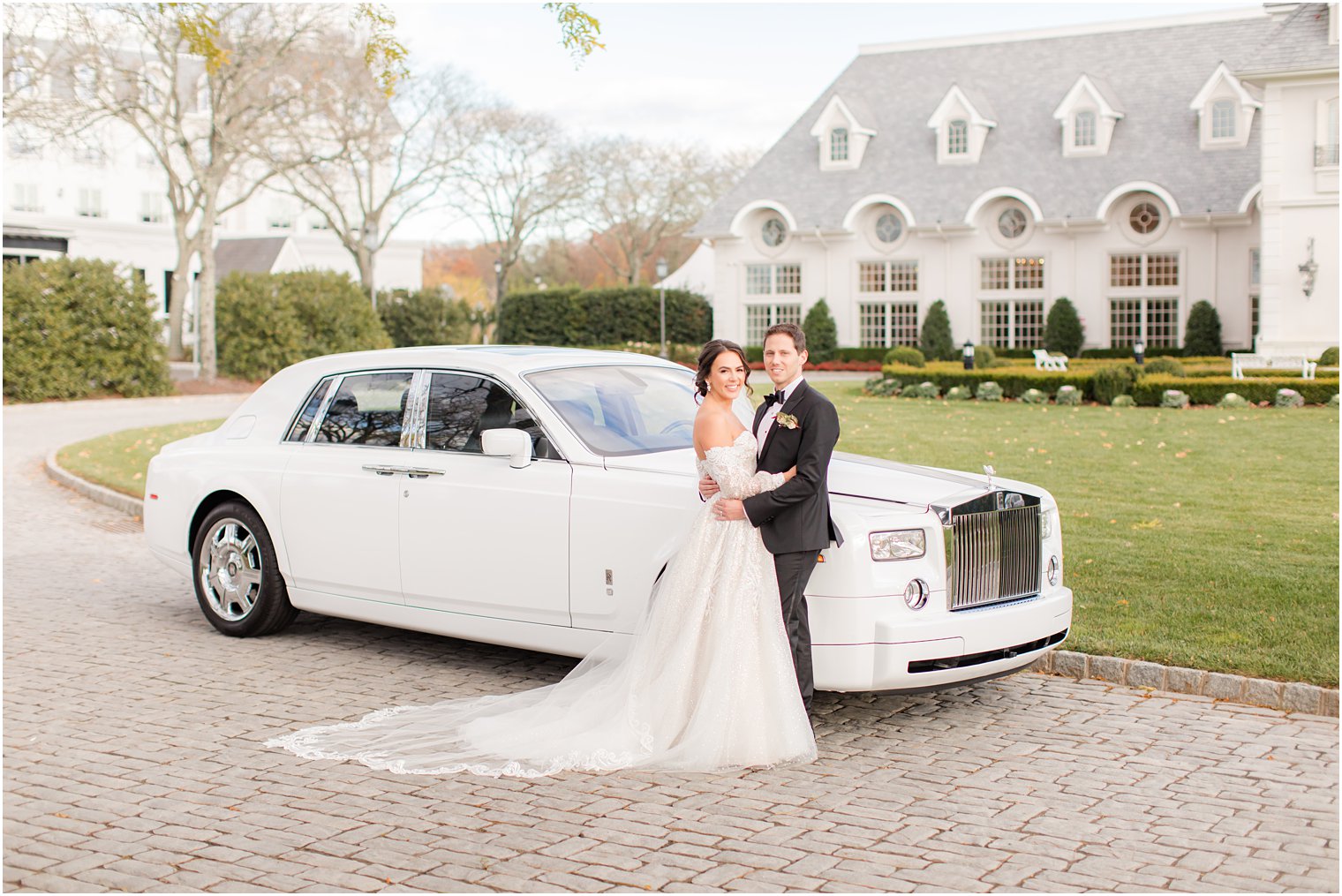 bride and groom hug by classic white car outside Park Chateau Estate