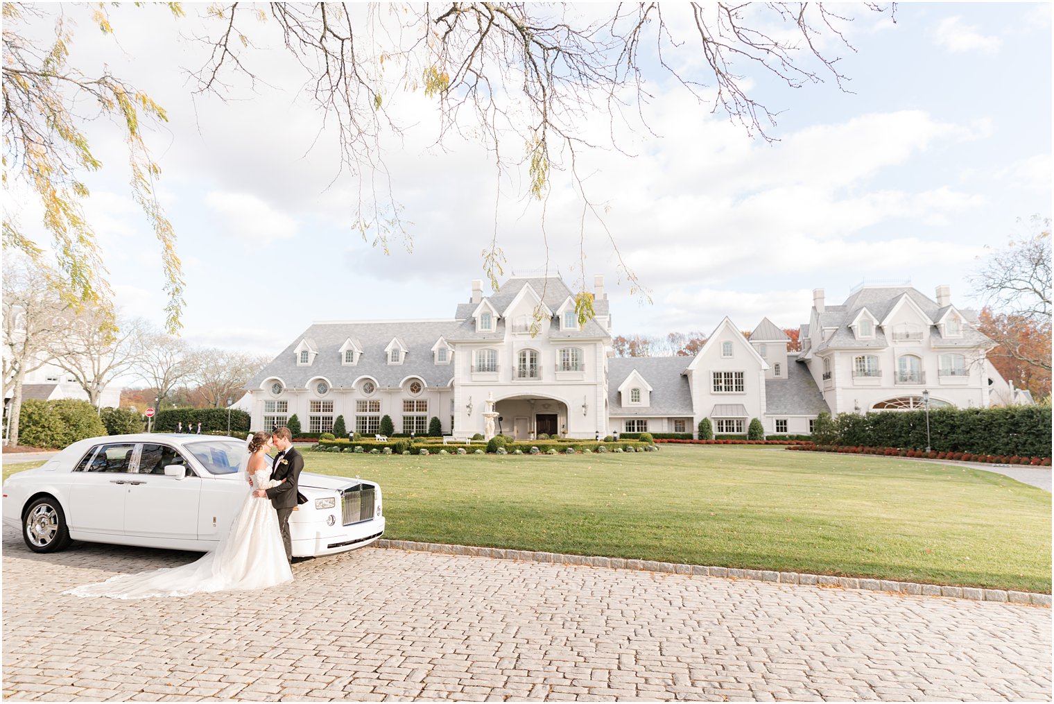 bride and groom pose by white car at Park Chateau Estate
