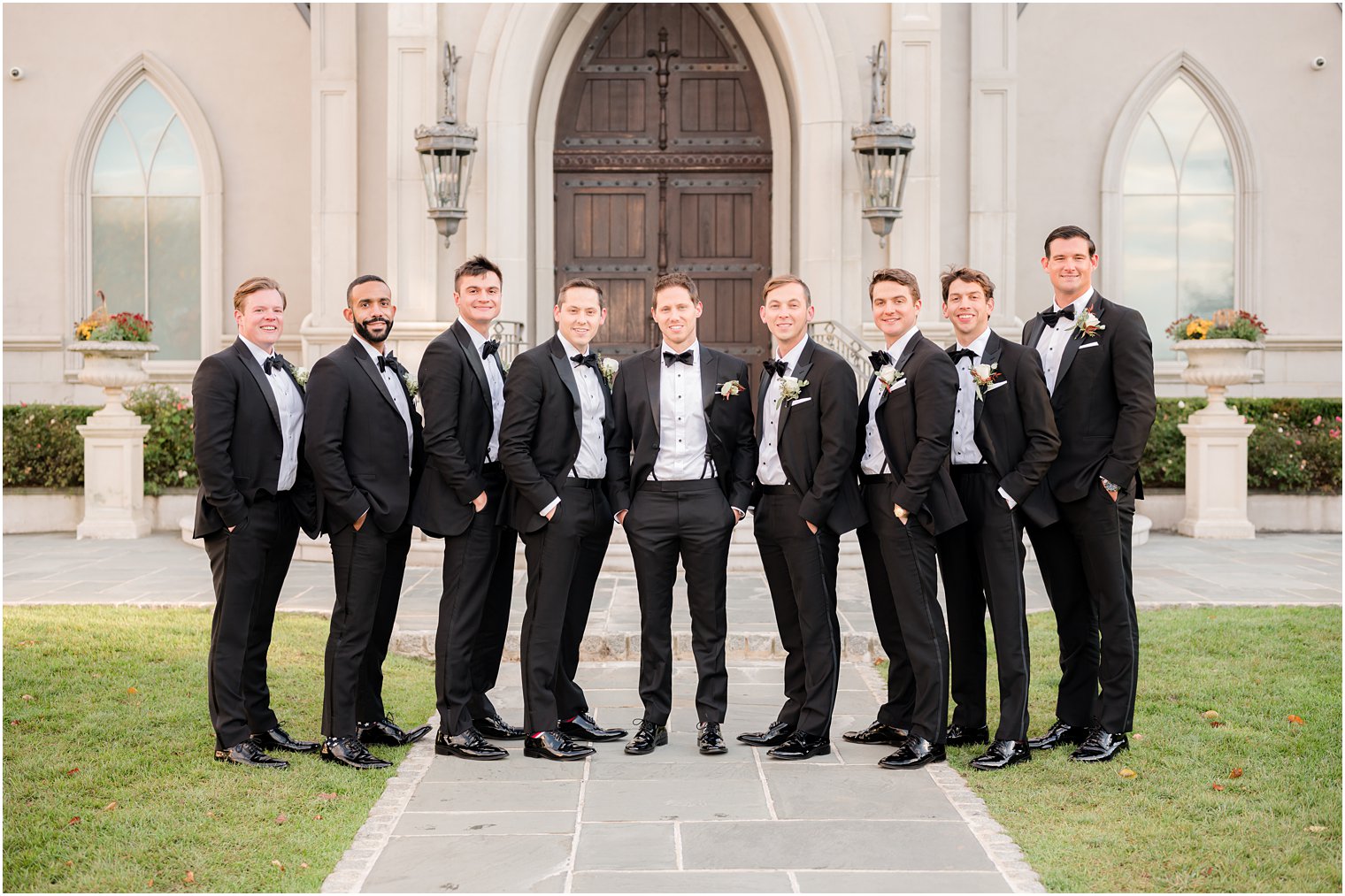groom stands with groomsmen in classic tuxes outside Park Chateau Estate chapel 