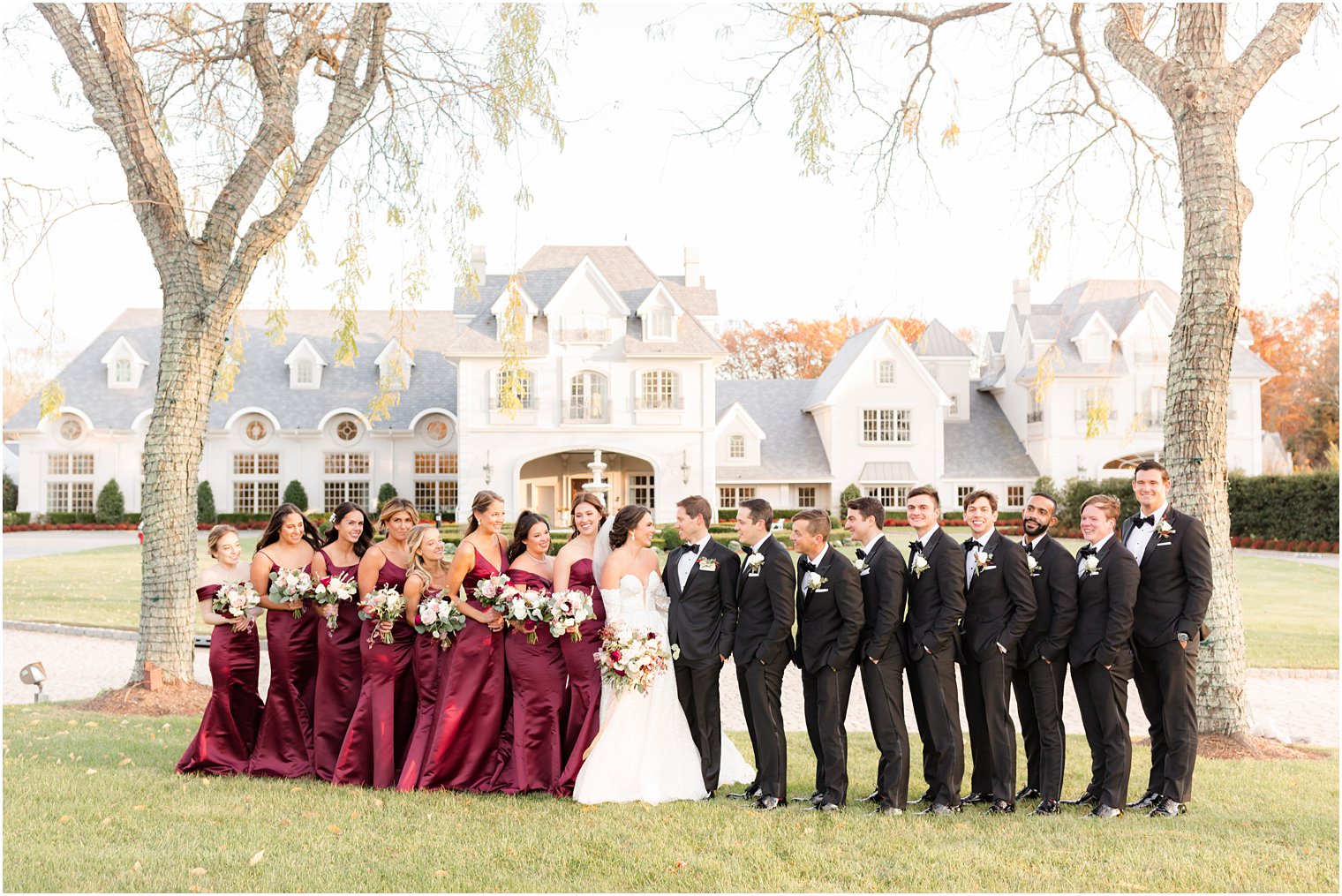 bride and groom smile with bridal party around them on the lawn of Park Chateau Estate