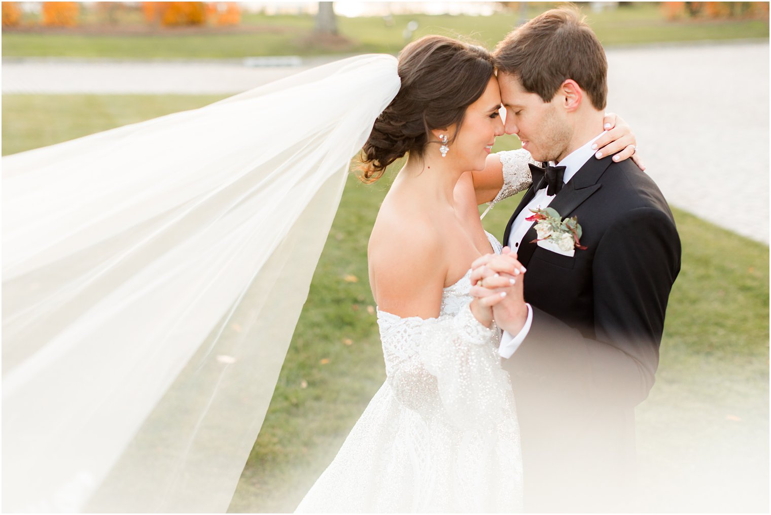 bride and groom stand with foreheads touching with bride's veil floating behind her 