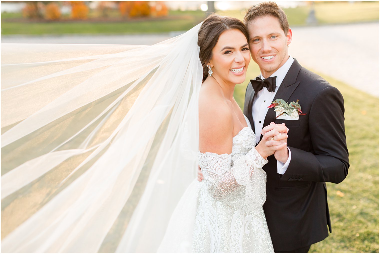 bride and groom hold hands with bride's veil behind her