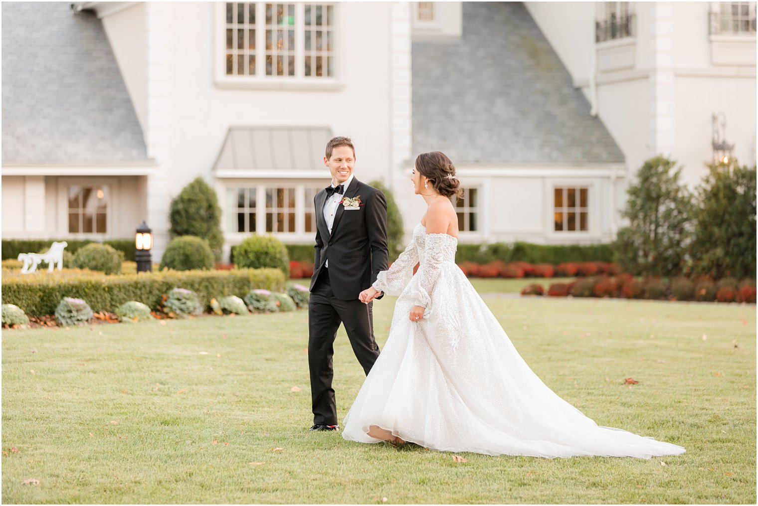 husband and wife hold hands walking on lawn of Park Chateau Estate