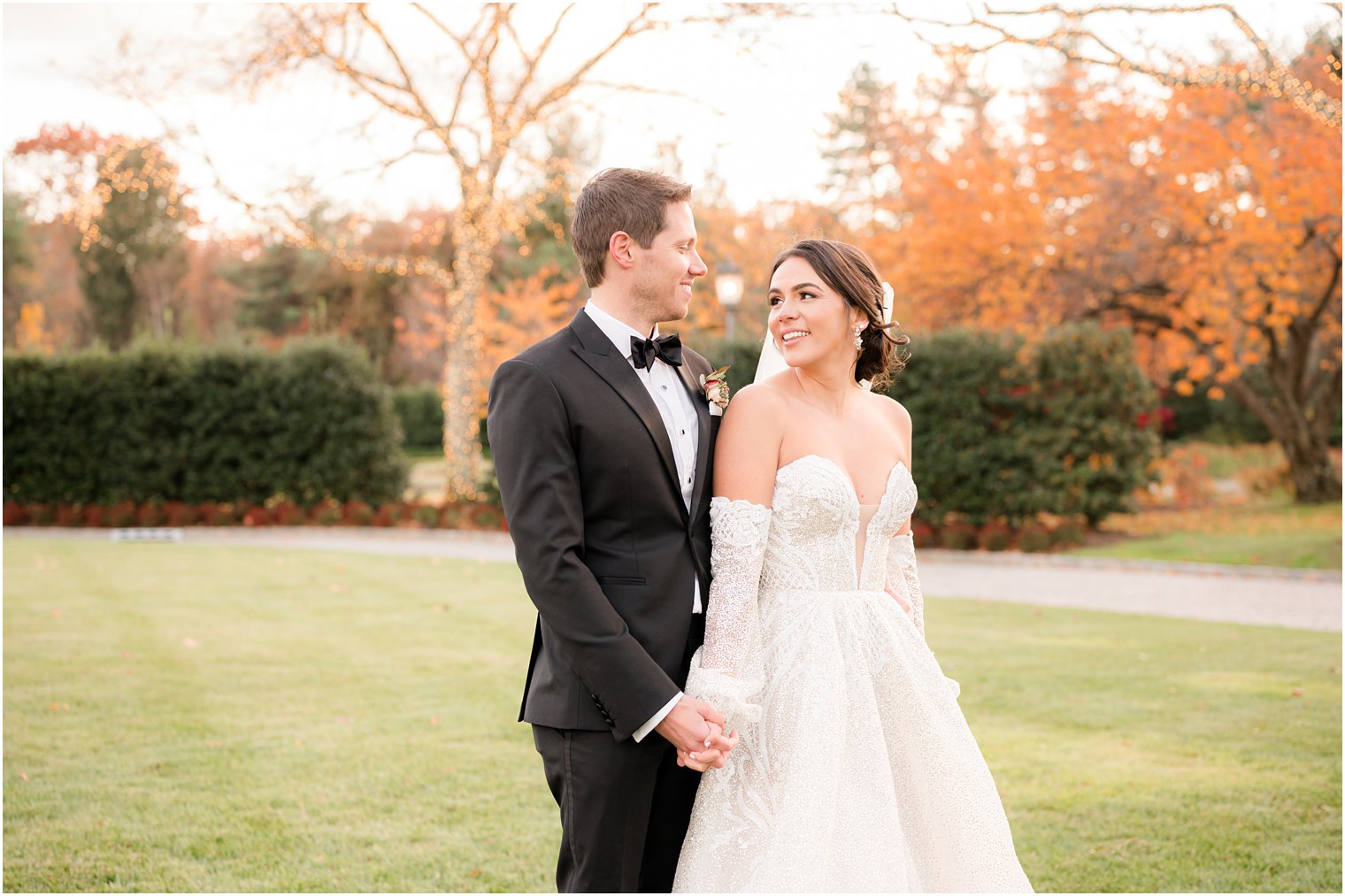 newlyweds hold hands walking through lawn of Park Chateau Estate