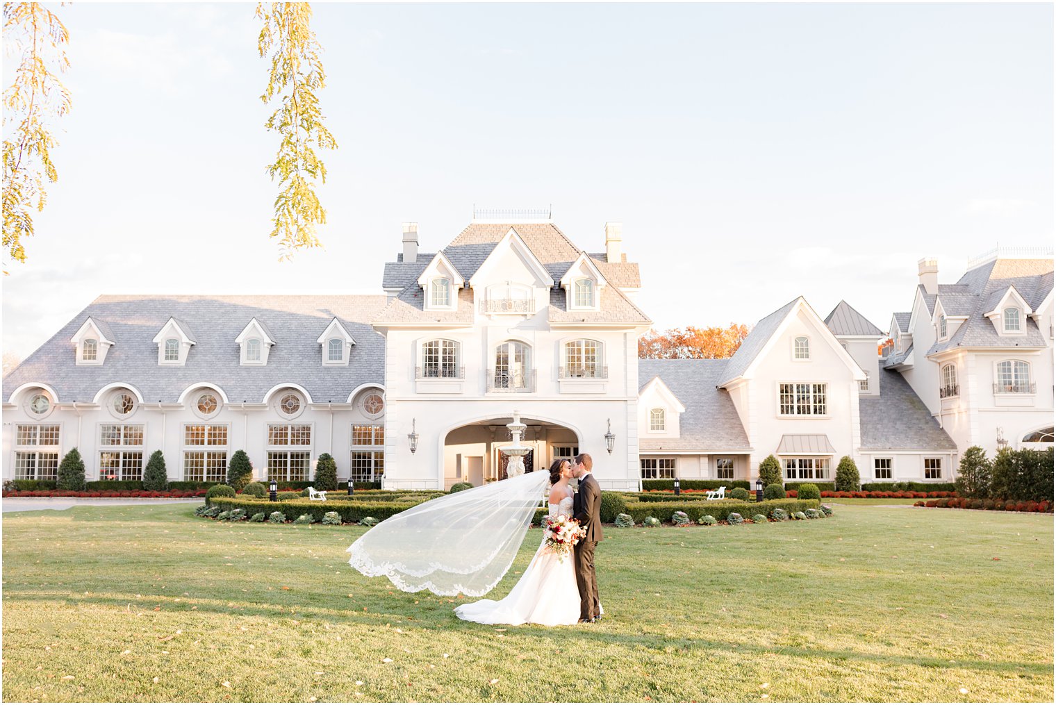 newlyweds kiss on the lawn in front of castle at Park Chateau Estate