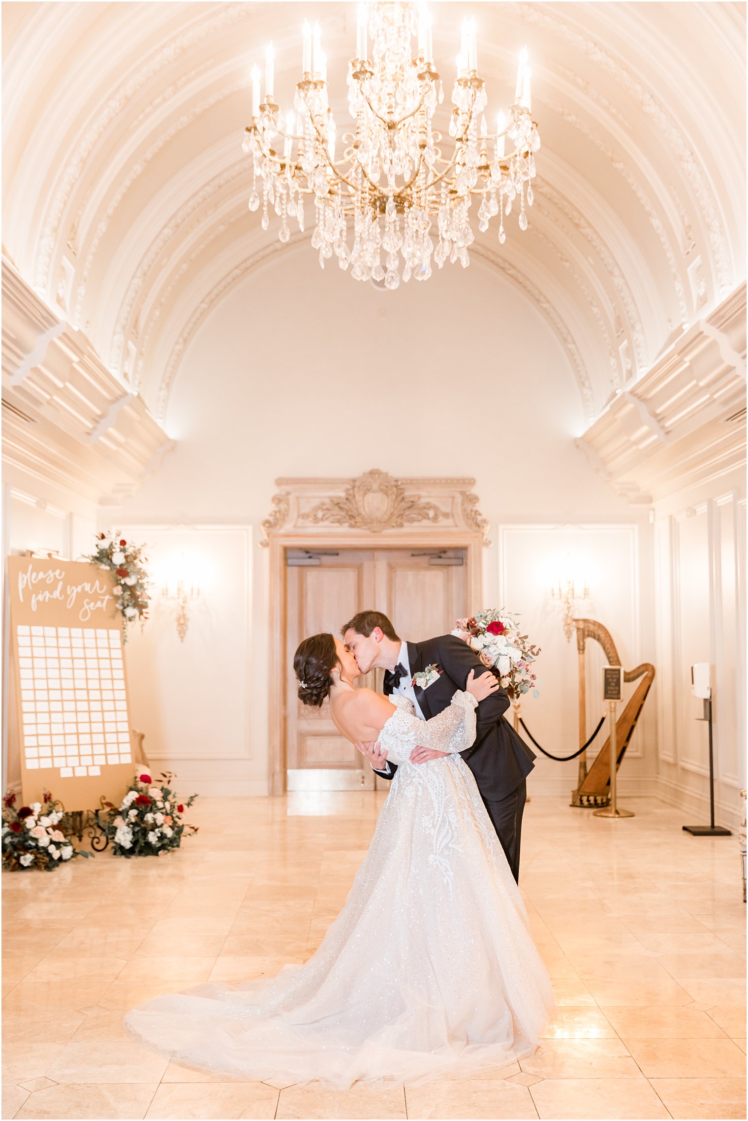 bride and groom kiss in hallway at Park Chateau Estate with seating chart behind them