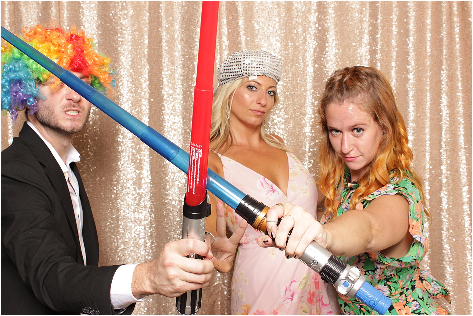 three friends play with light sabers during NJ photo booth