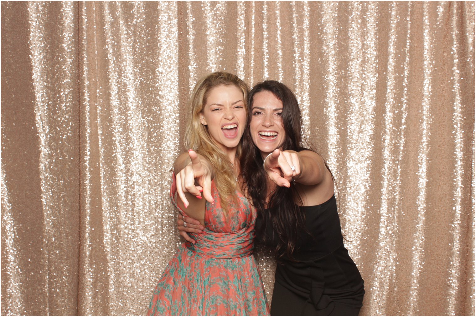 two women sing pointing at the camera during photo booth