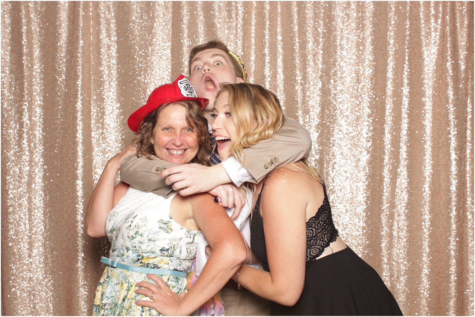 guy hugs mom and sister during photo booth fun against rose gold backdrop