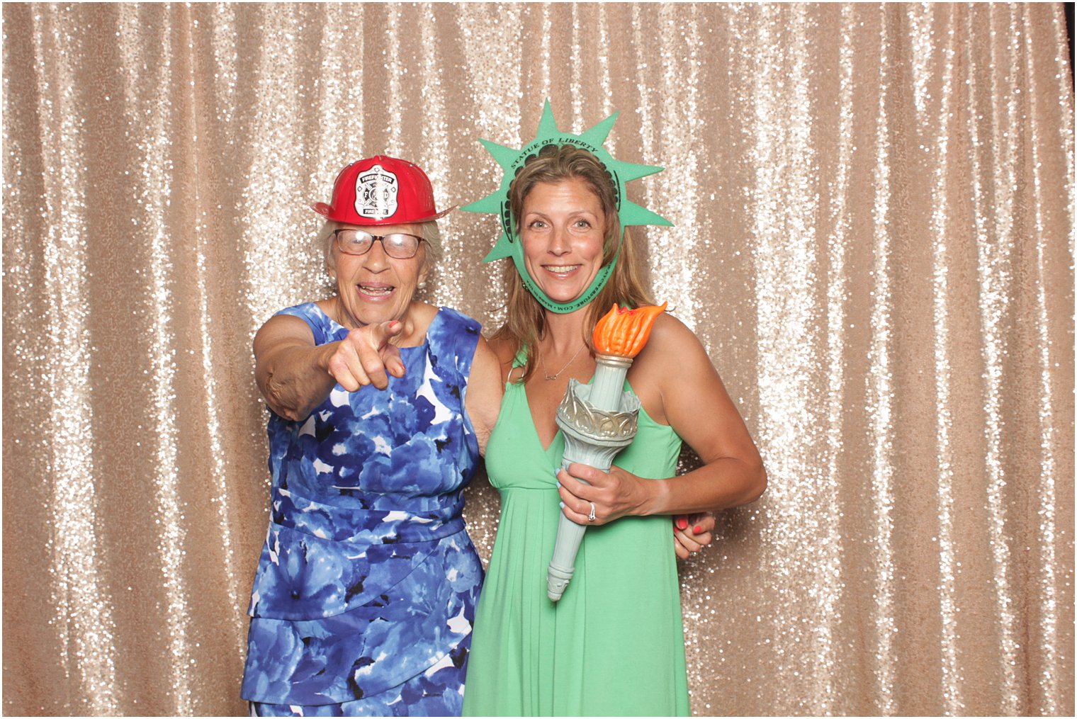 woman wears firefighter hat while second woman wears lady Liberty props in Minerals Resort photo booth