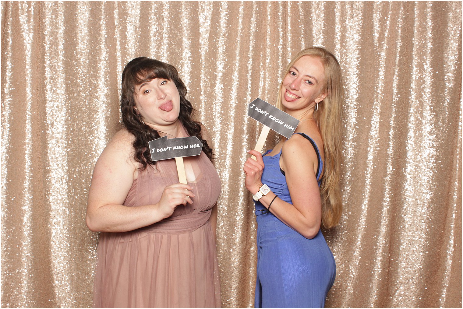 women laugh together holding signs in photo booth