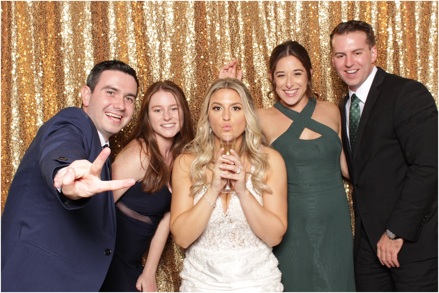 bride poses with guests during reception photo booth 