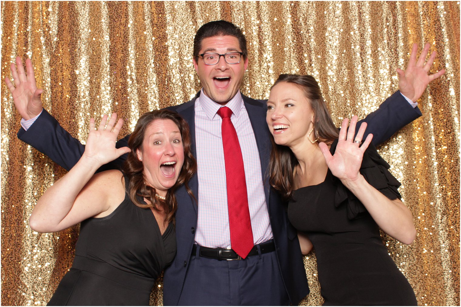 three guests pose by gold curtain 