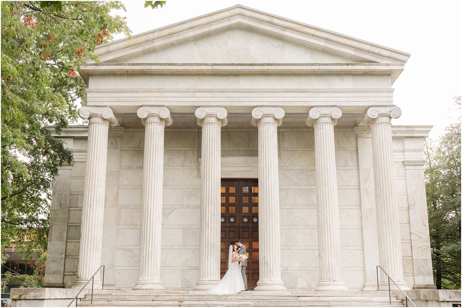 bride and groom stand on steps of Clio and Whig during wedding portraits at Princeton University 