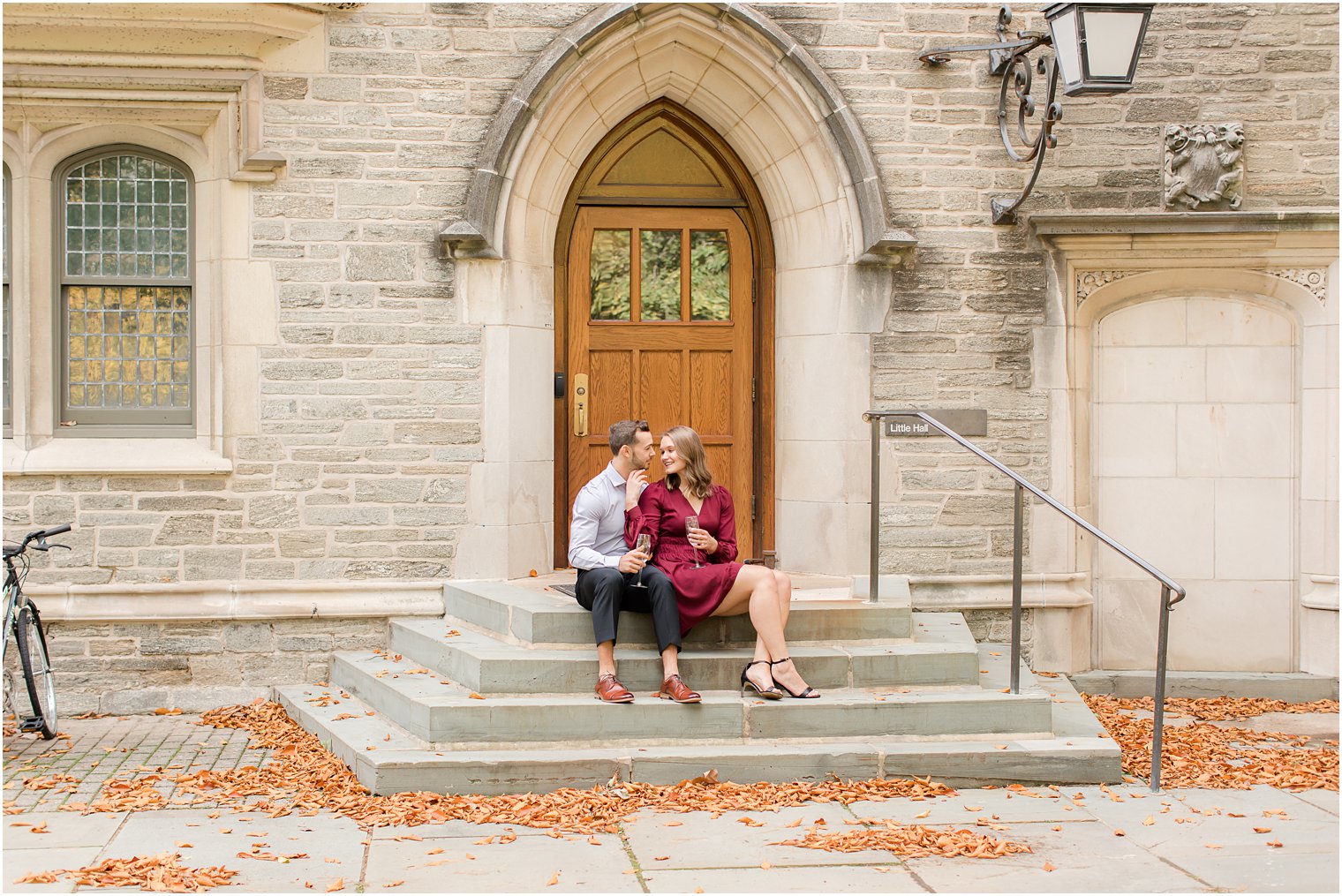 engaged couple sits on the steps during fall engagement photos at Princeton University