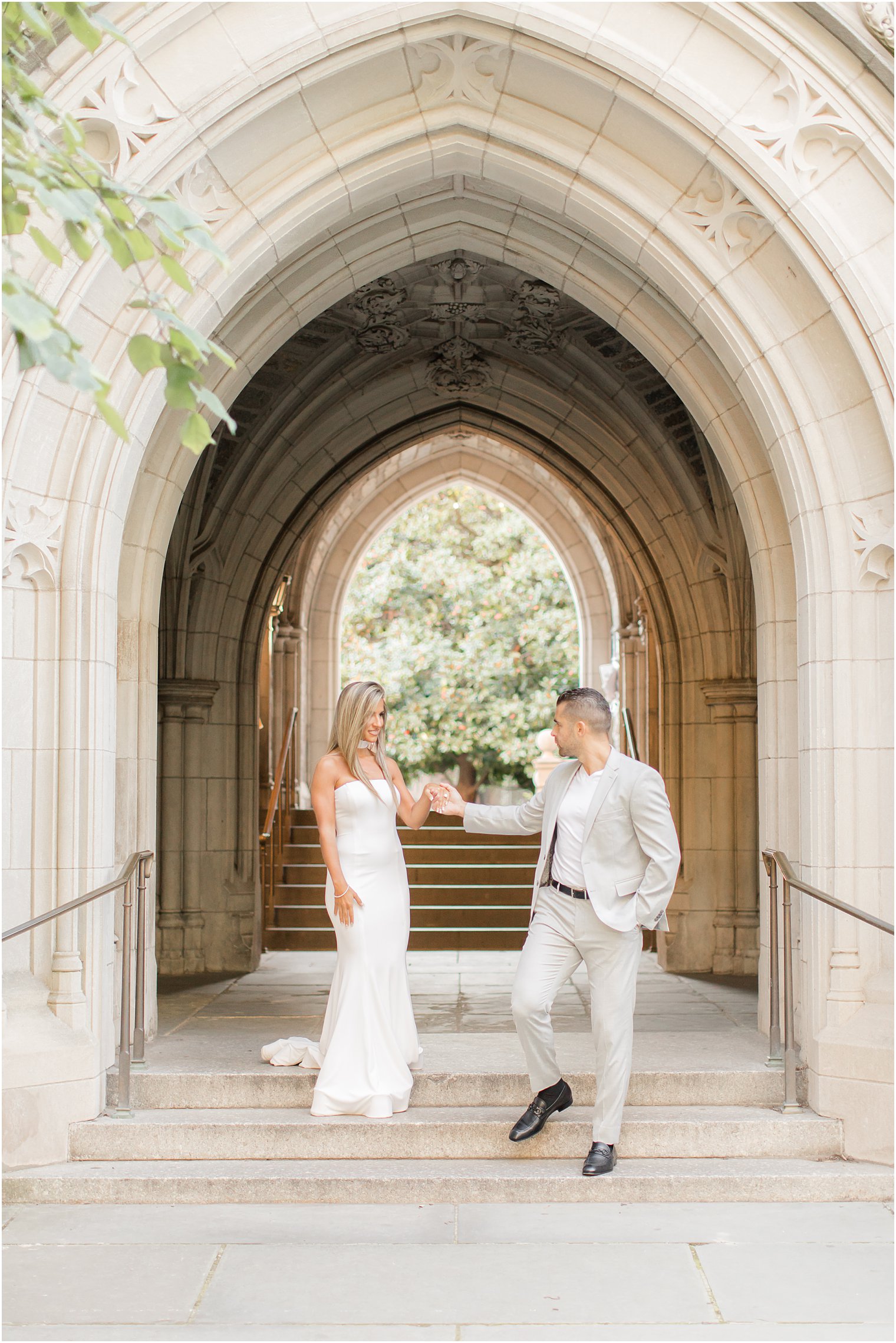 engaged couple walks down steps of Rockefeller College during engagement photos at Princeton University