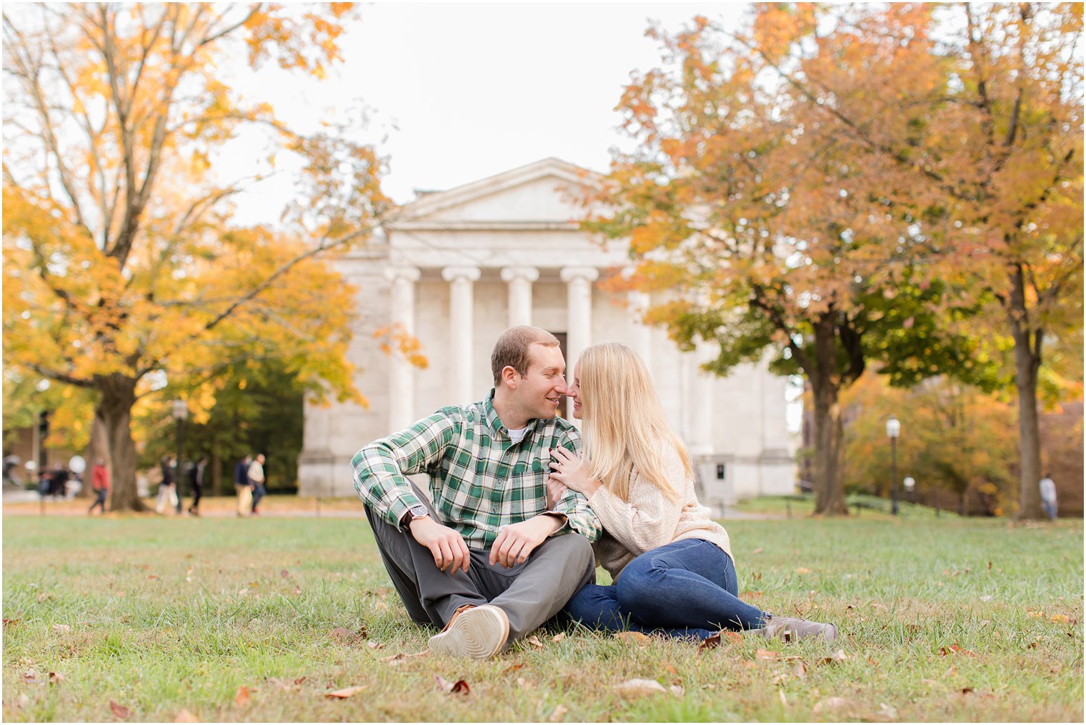 couple sits on lawn during fall engagement photos at Princeton University