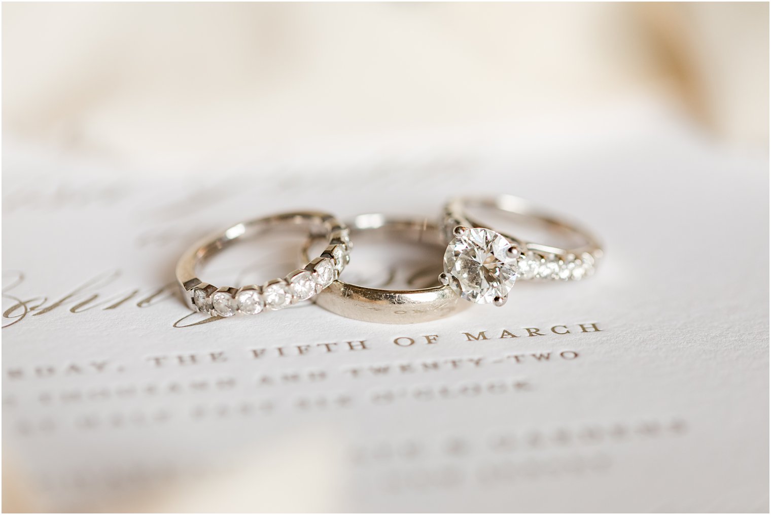 three wedding bands rest on invitation suite before Park Chateau winter wedding
