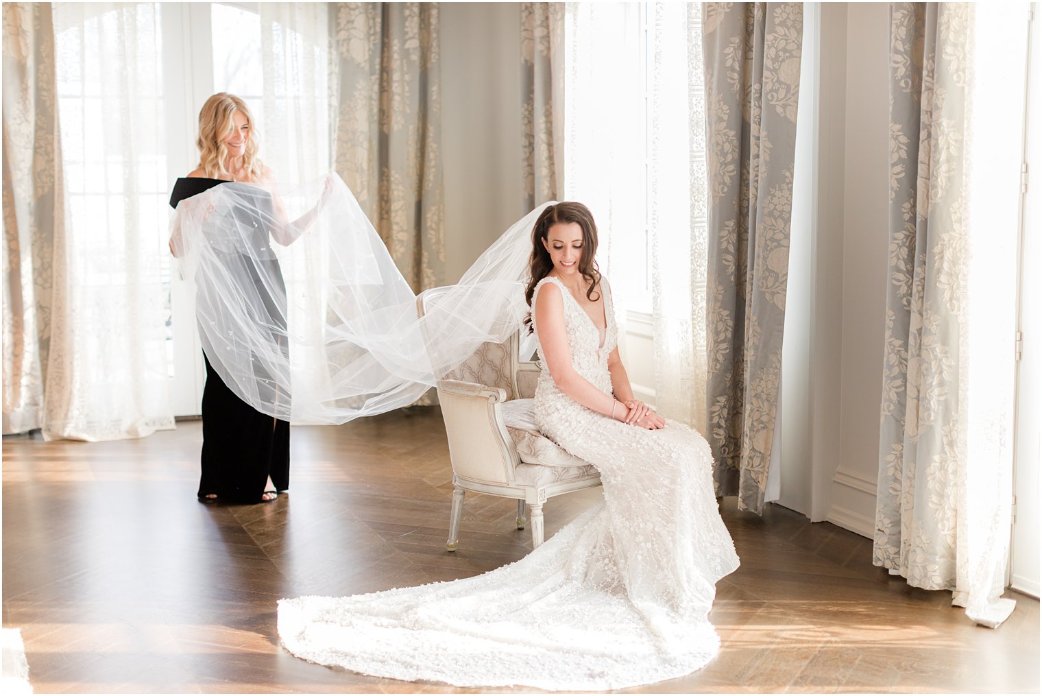 mother helps bride with veil while she sits in chair in bridal suite at Park Chateau Estate 