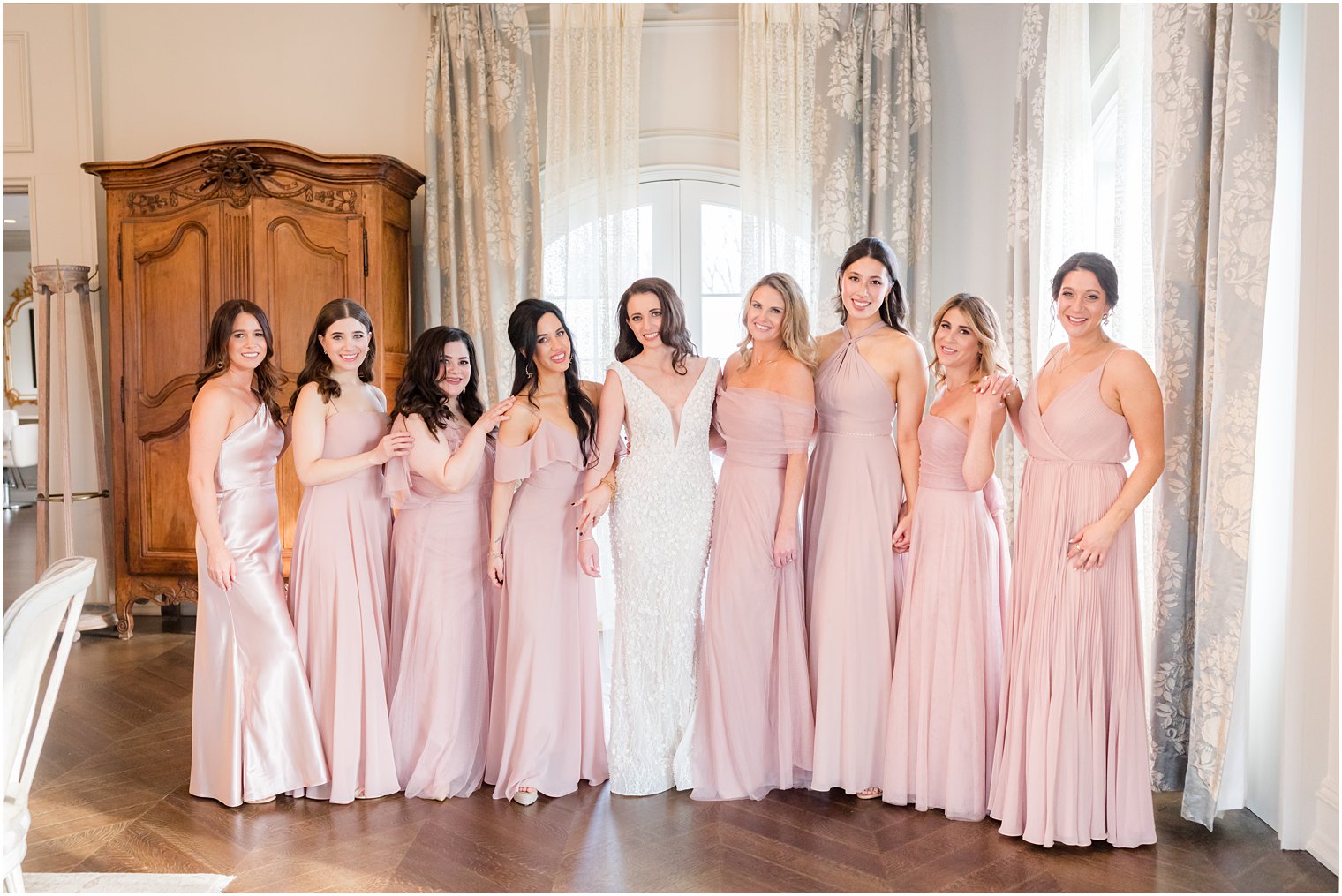 bride poses with bridesmaids in pale pink gowns before Park Chateau winter wedding