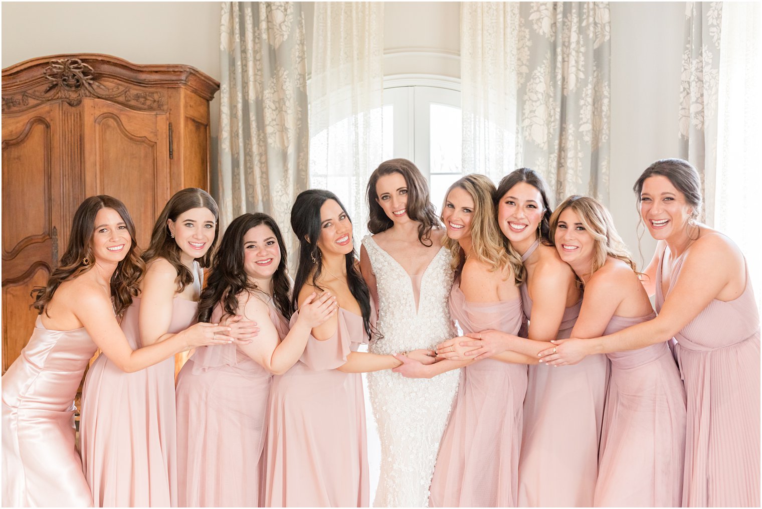 bride poses with bridesmaids in pastel pink gowns in bridal suite at Park Chateau Estate 