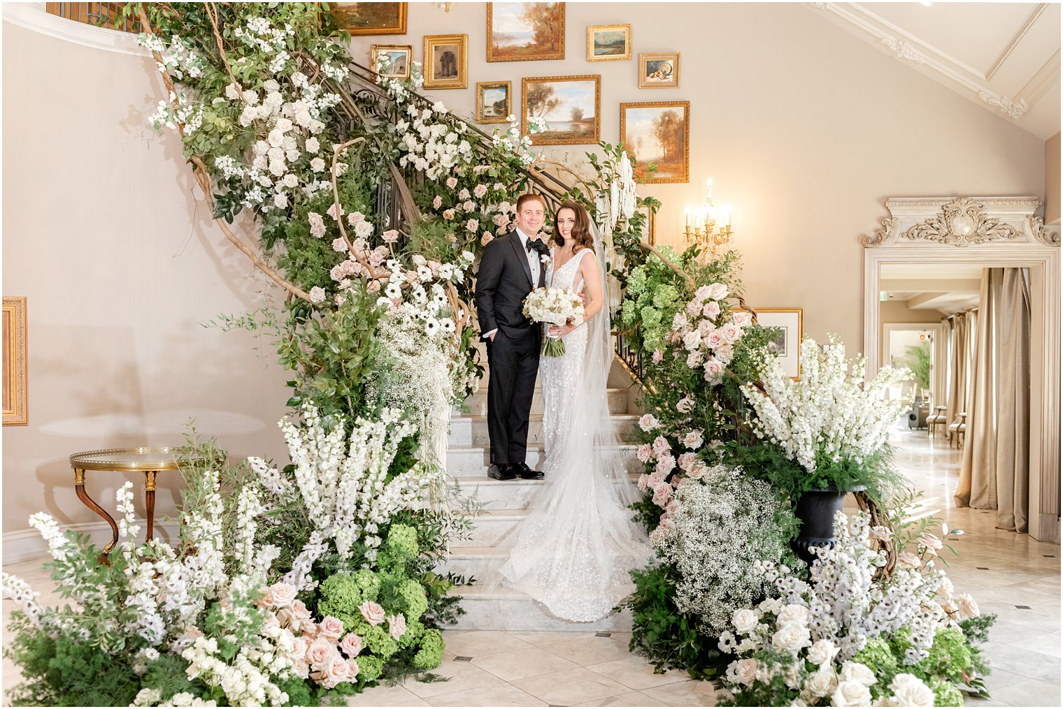 bride and groom pose on steps covered in greenery and flowers at Park Chateau Estate 