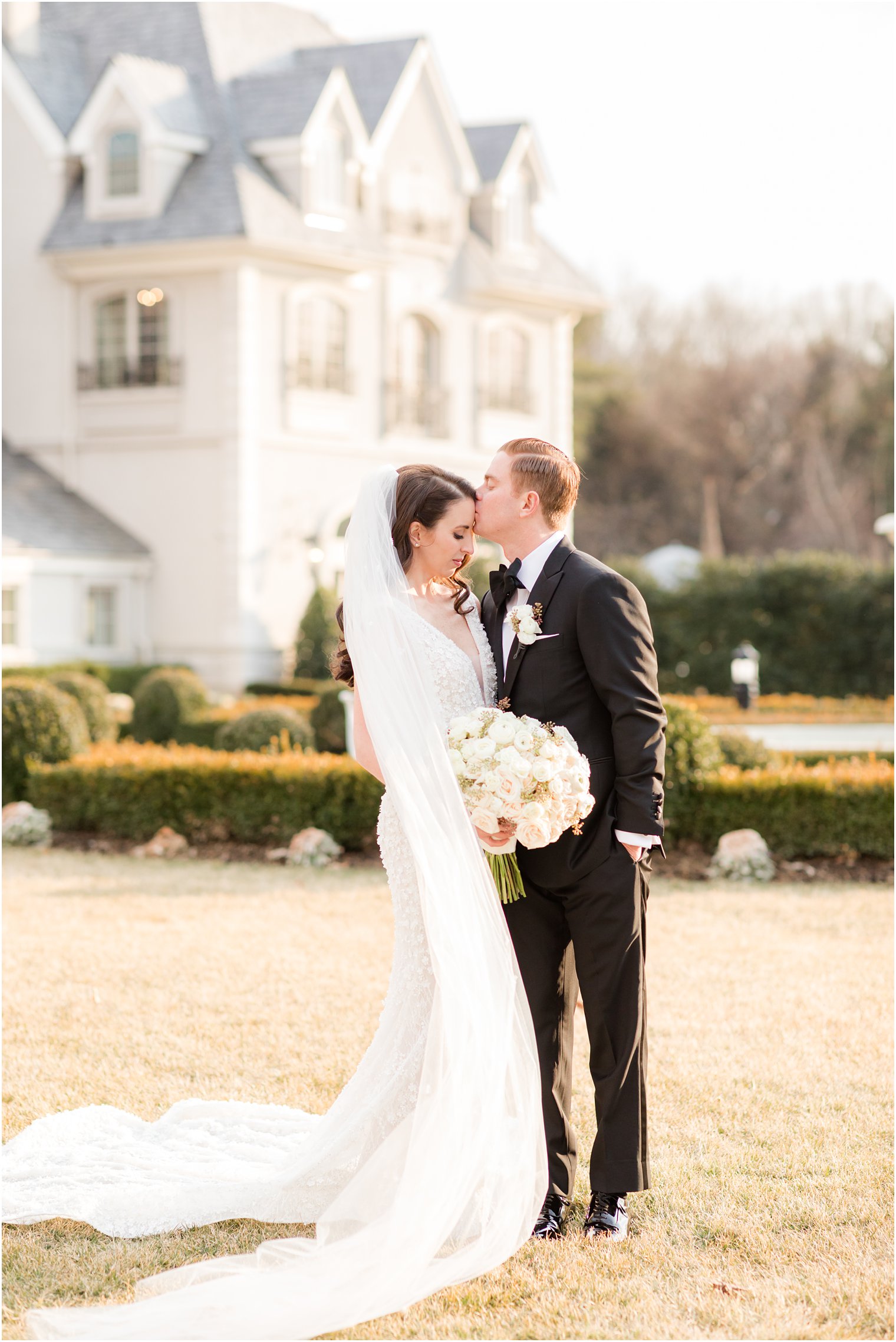 groom kisses bride's forehead during NJ wedding portraits 