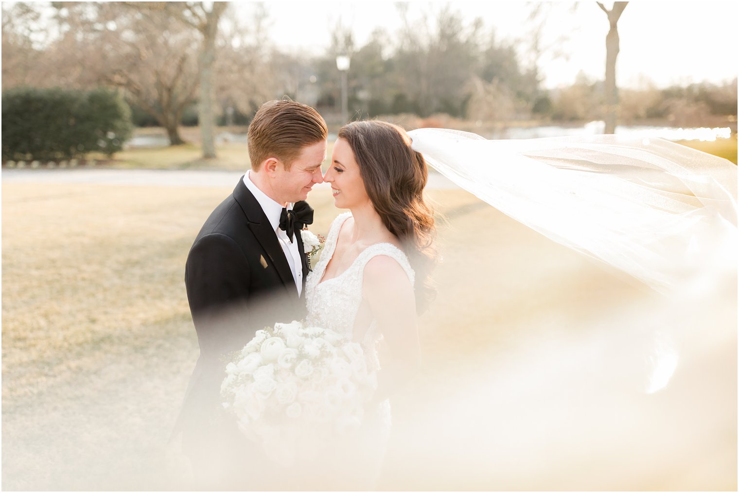 bride and groom nuzzle noses during portraits on the lawn before Park Chateau winter wedding