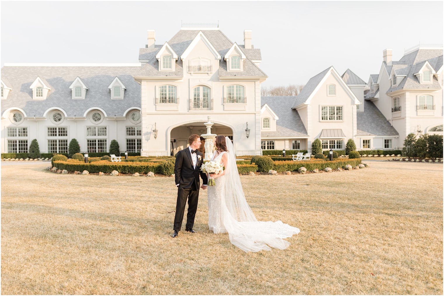 bride and groom hold hands smiling on lawn at Park Chateau Estate 