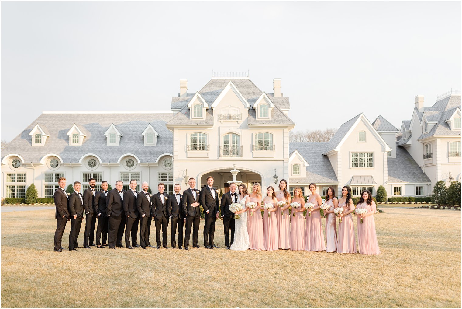 bride and groom stand with wedding party on lawn at Park Chateau Estate 