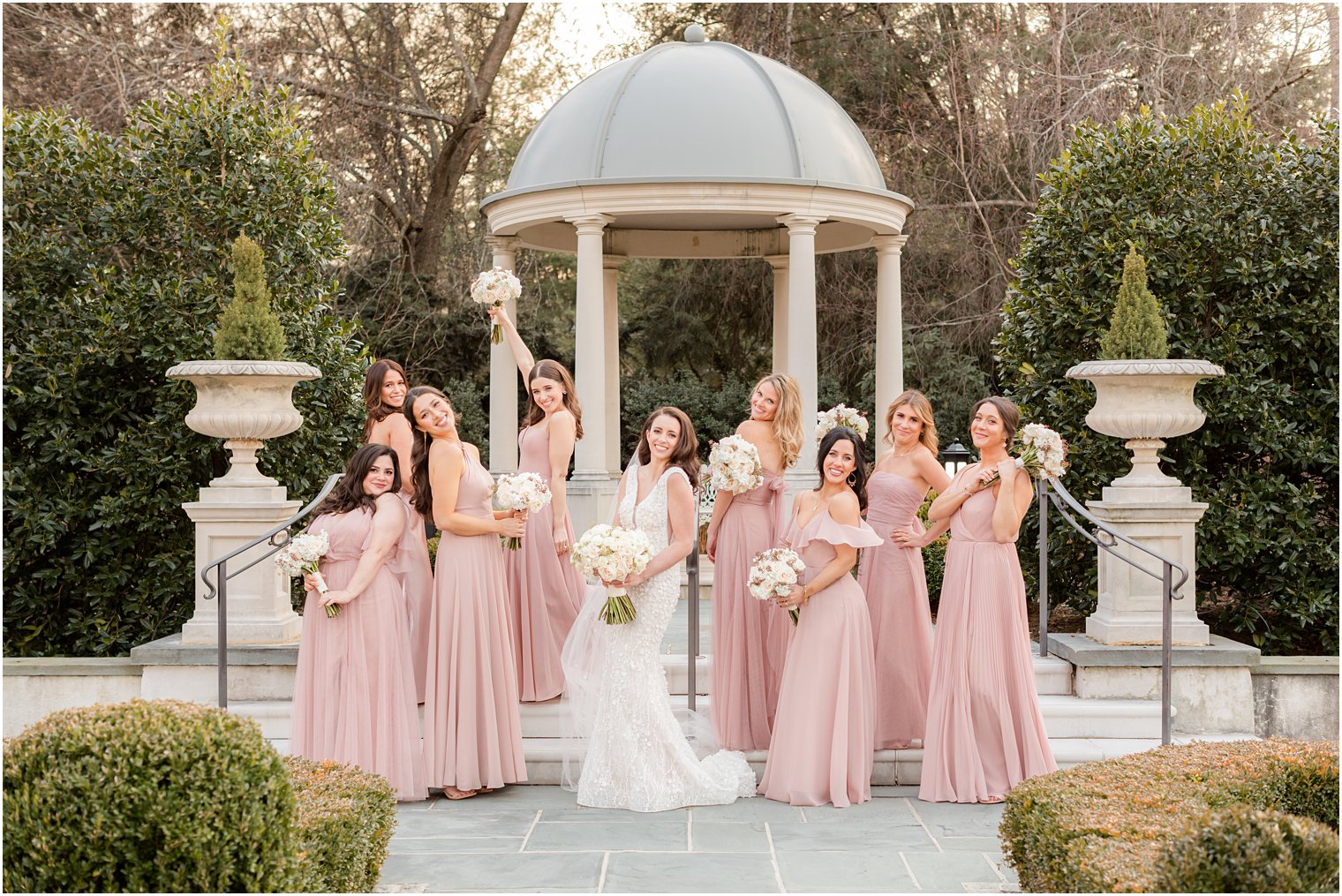 bride and bridesmaids pose by gazebo in gardens at Park Chateau Estate 