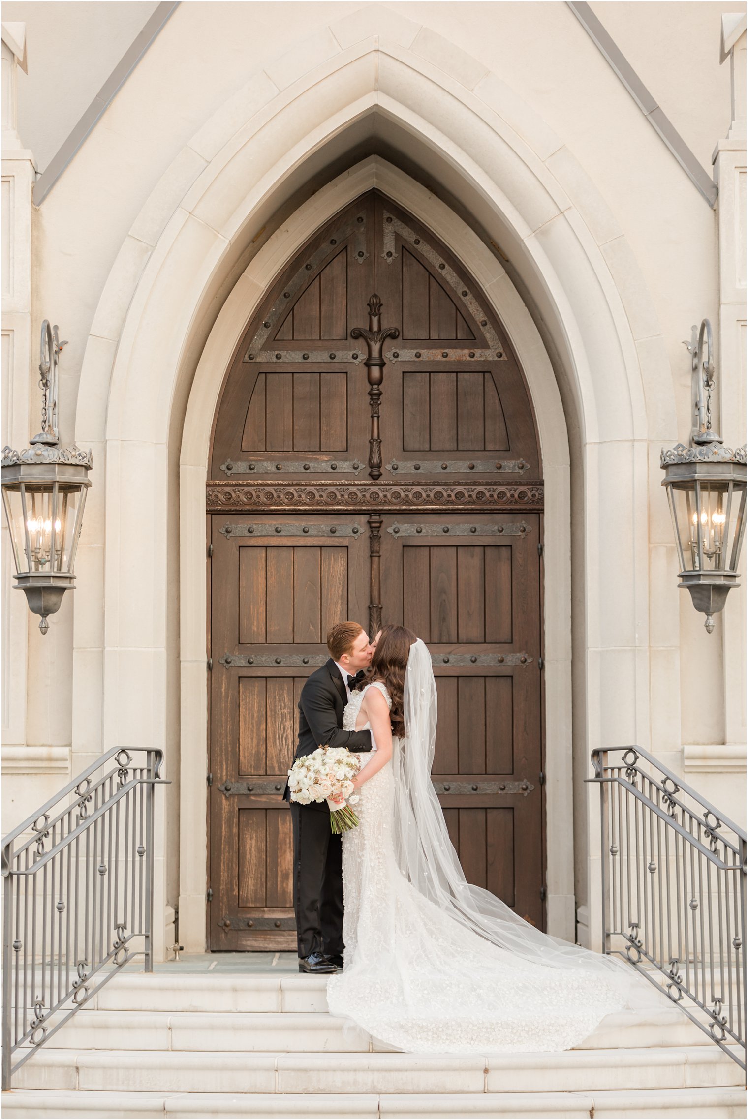 bride and groom kiss by wooden doors at chapel at Park Chateau Estate 