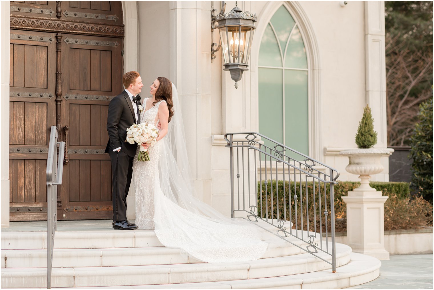 bride and groom smile together on steps at Park Chateau Estate chapel 