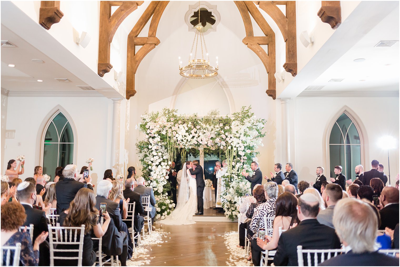 bride and groom kiss during NJ wedding ceremony under floral canopy 