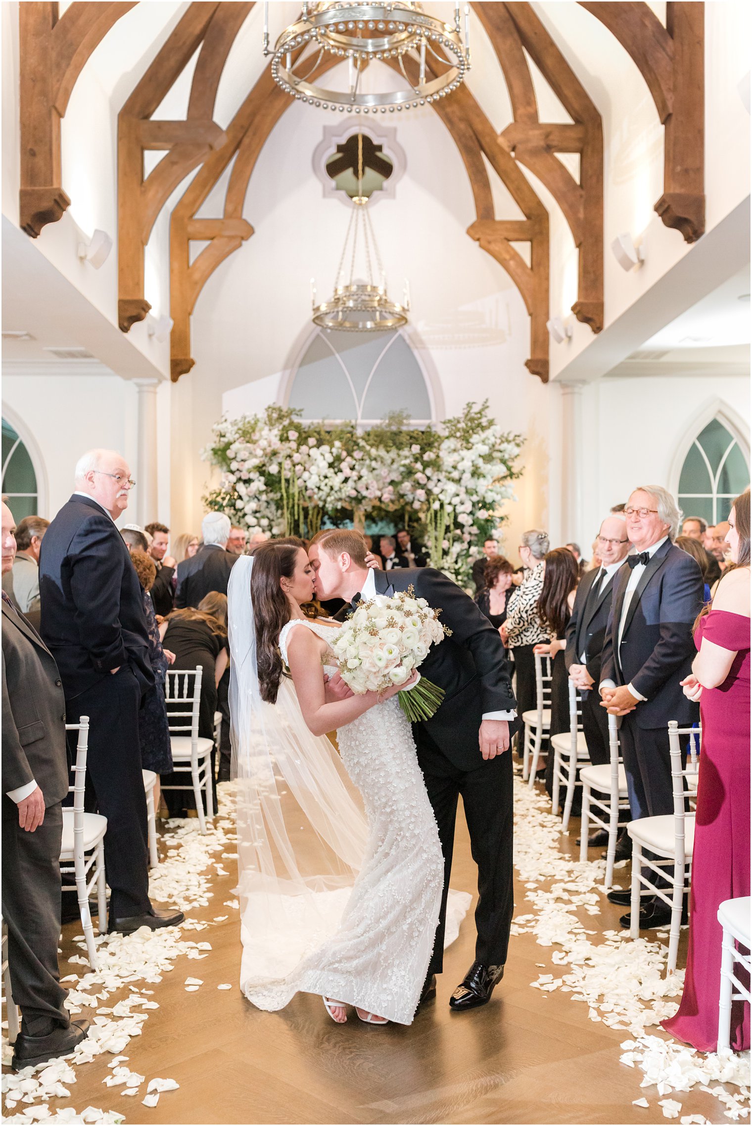 bride and groom kiss walking up aisle at Park Chateau 