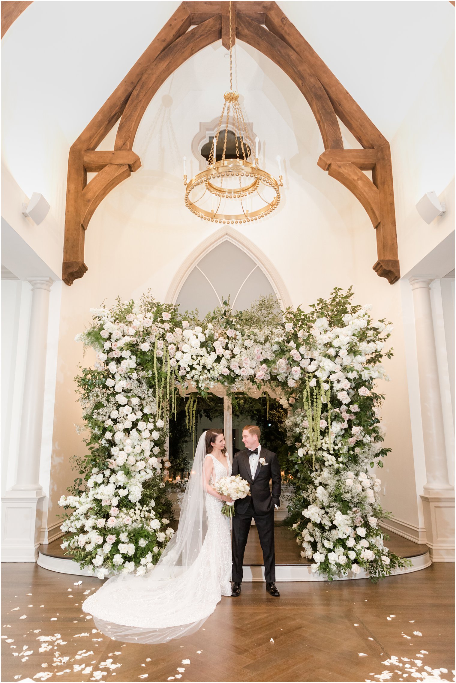 bride and groom stand together under floral canopy after wedding ceremony 
