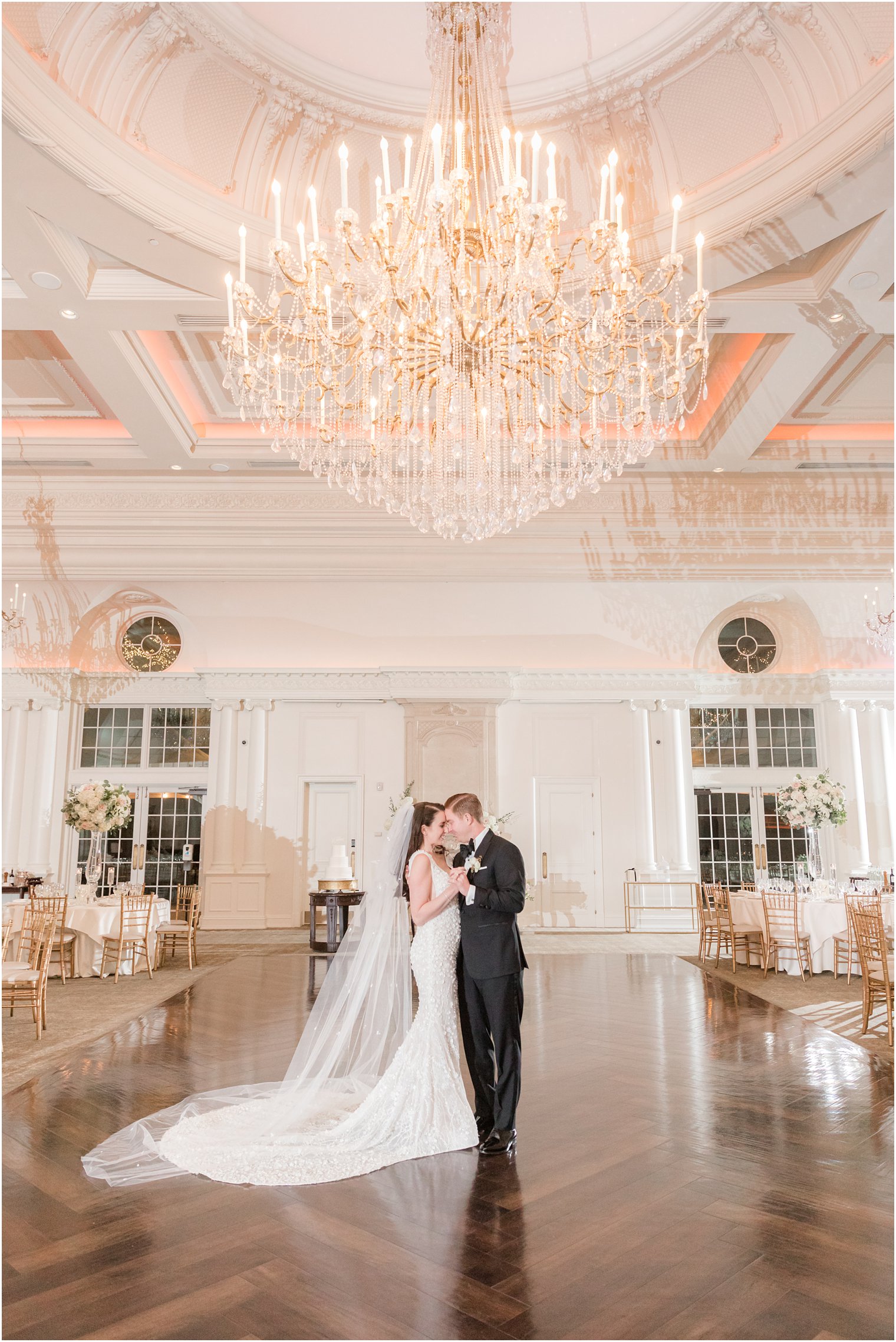 bride and groom pose in empty ballroom before Park Chateau winter wedding reception 