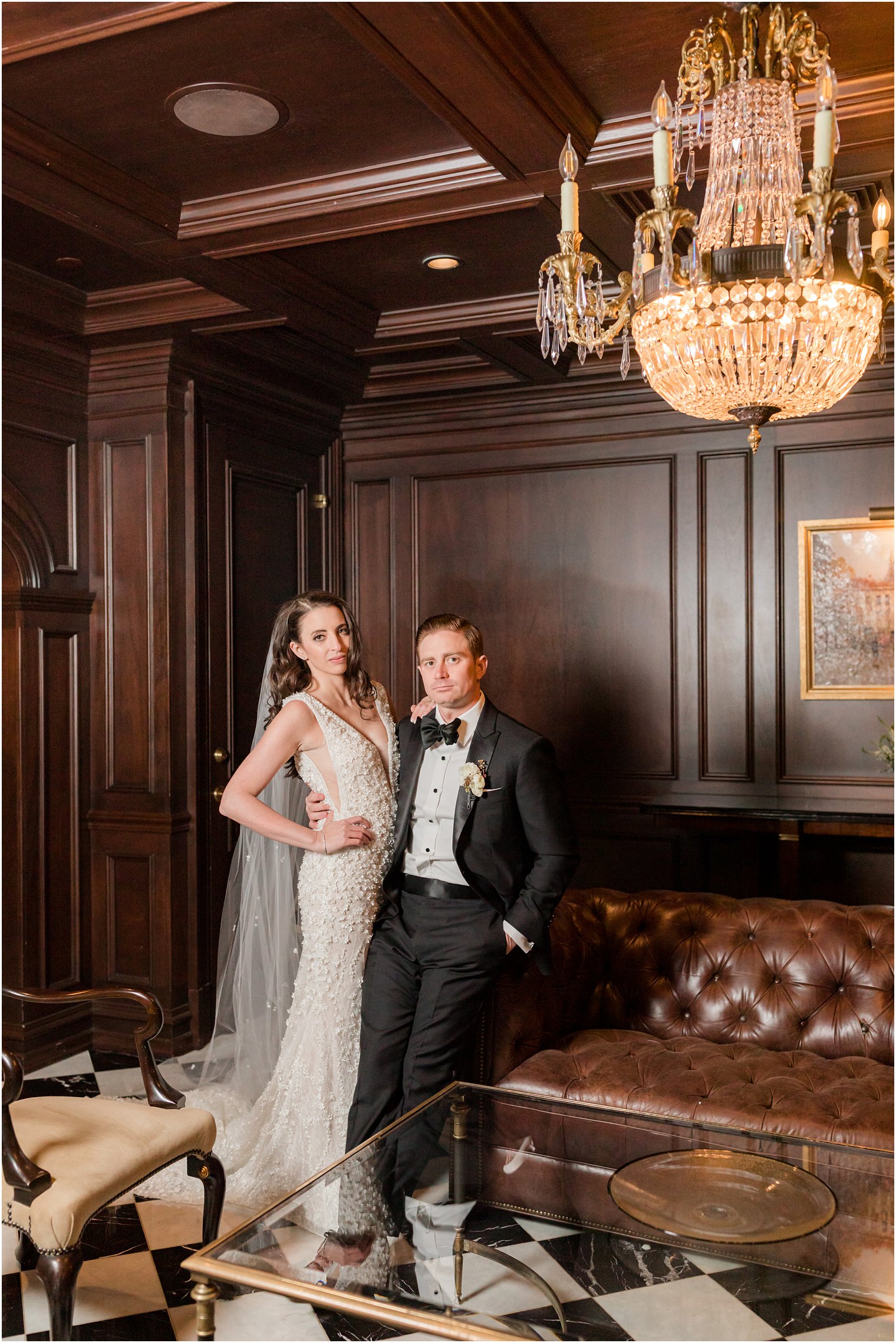 bride and groom lean against leather couch hugging together during portraits in Park Chateau Estate 