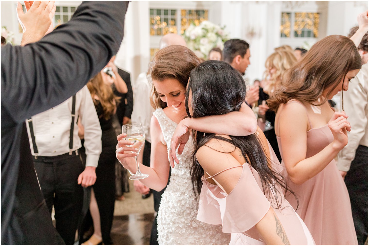bride hugs bridesmaid during dancing at East Brunswick NJ wedding reception 
