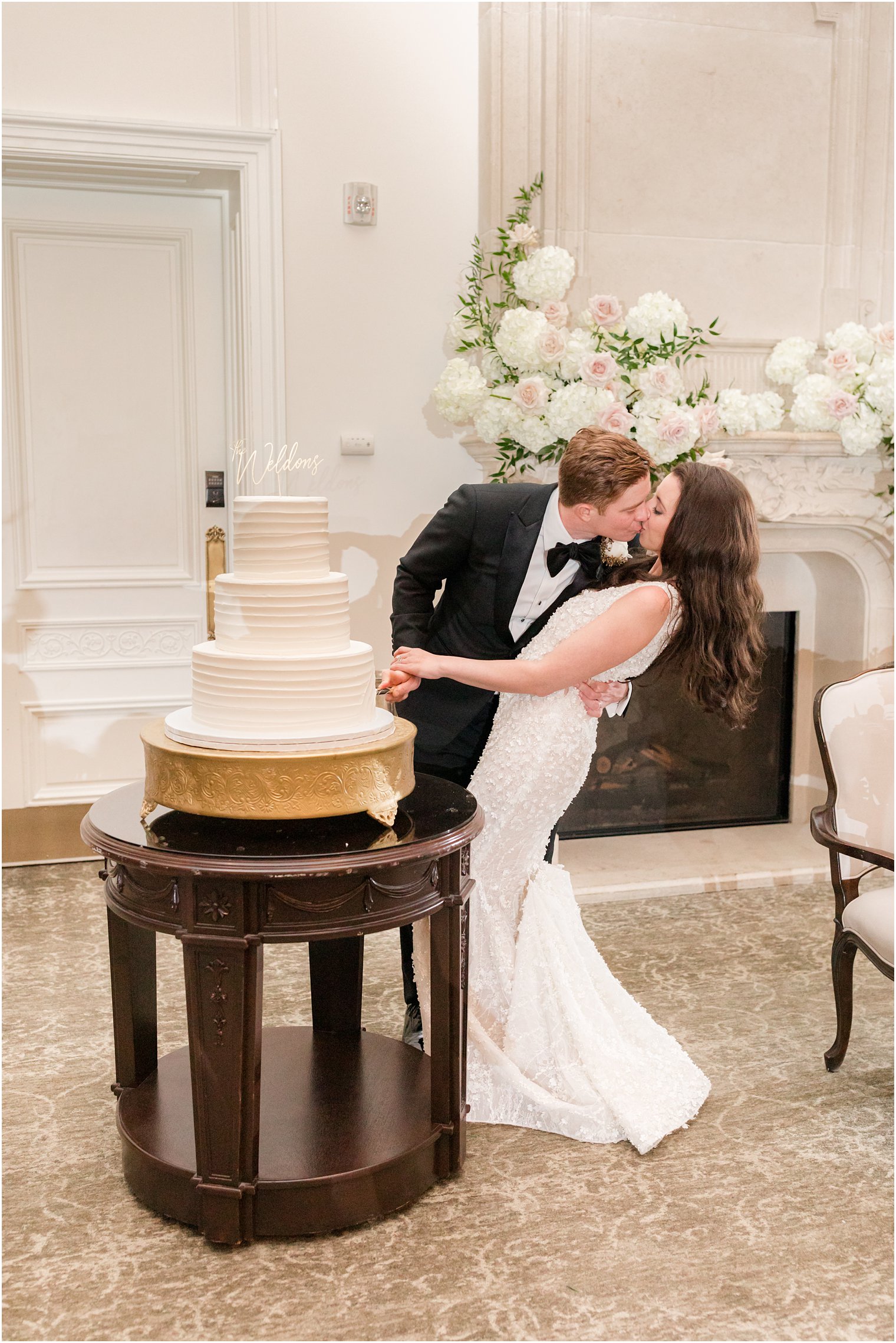 bride and groom kiss while cutting wedding cake at East Brunswick NJ wedding reception 
