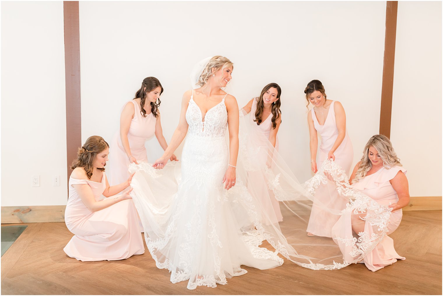 bridesmaids helping bride into her wedding dress and cathedral veil at Renault Winery in Egg Harbor Twp NJ