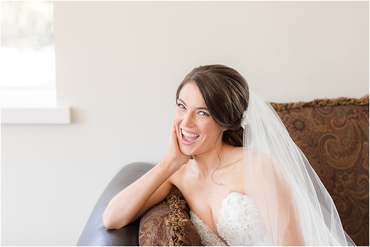 bride laughs during portraits in leather couch