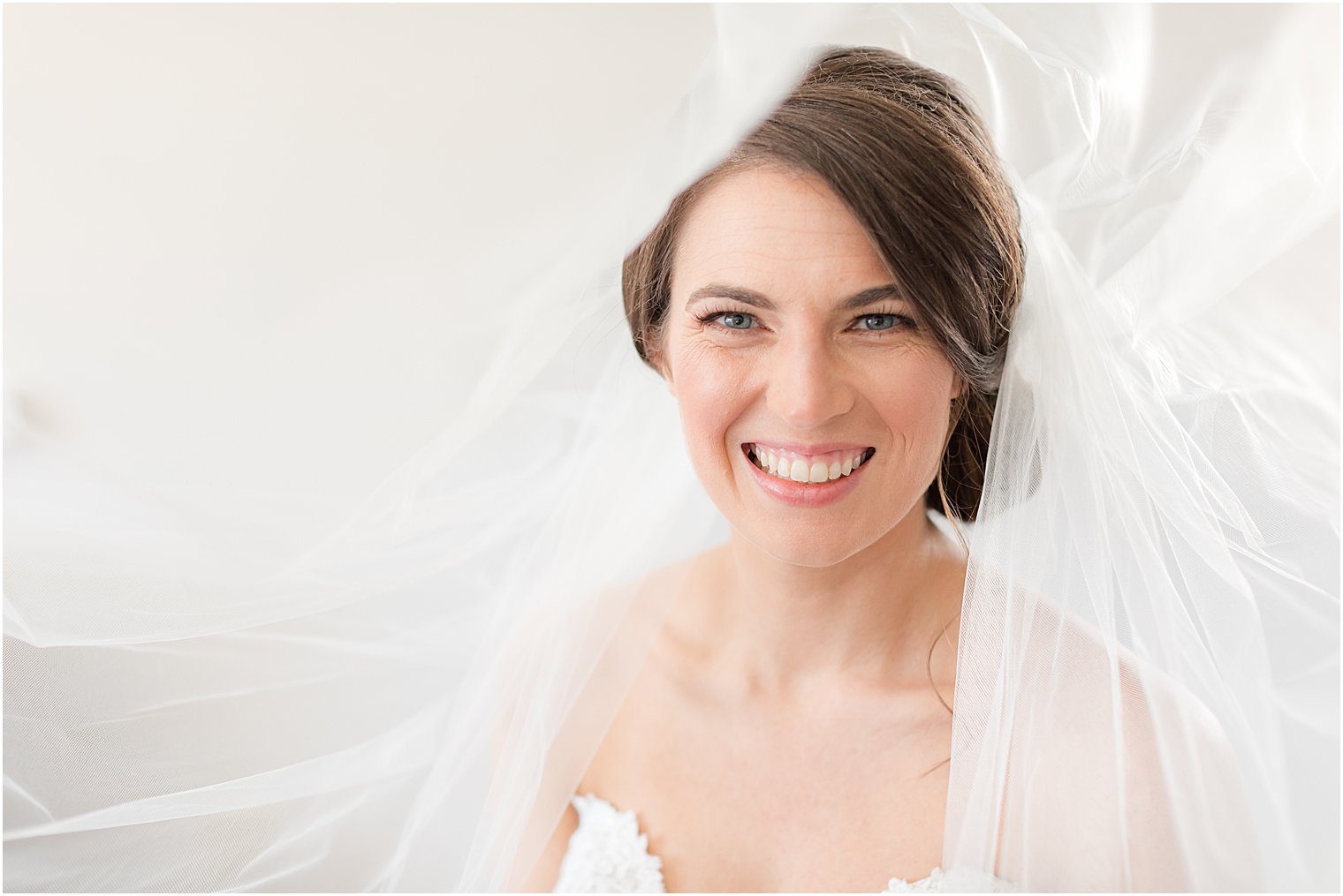 bride smiles under veil during NJ bridal portraits 
