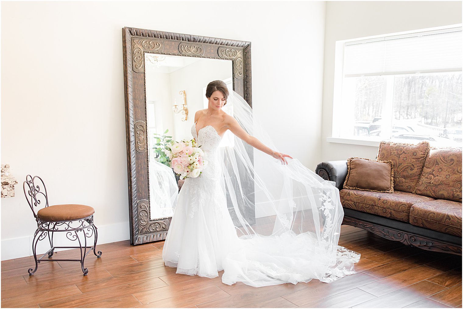 bride holds out veil above wedding dress