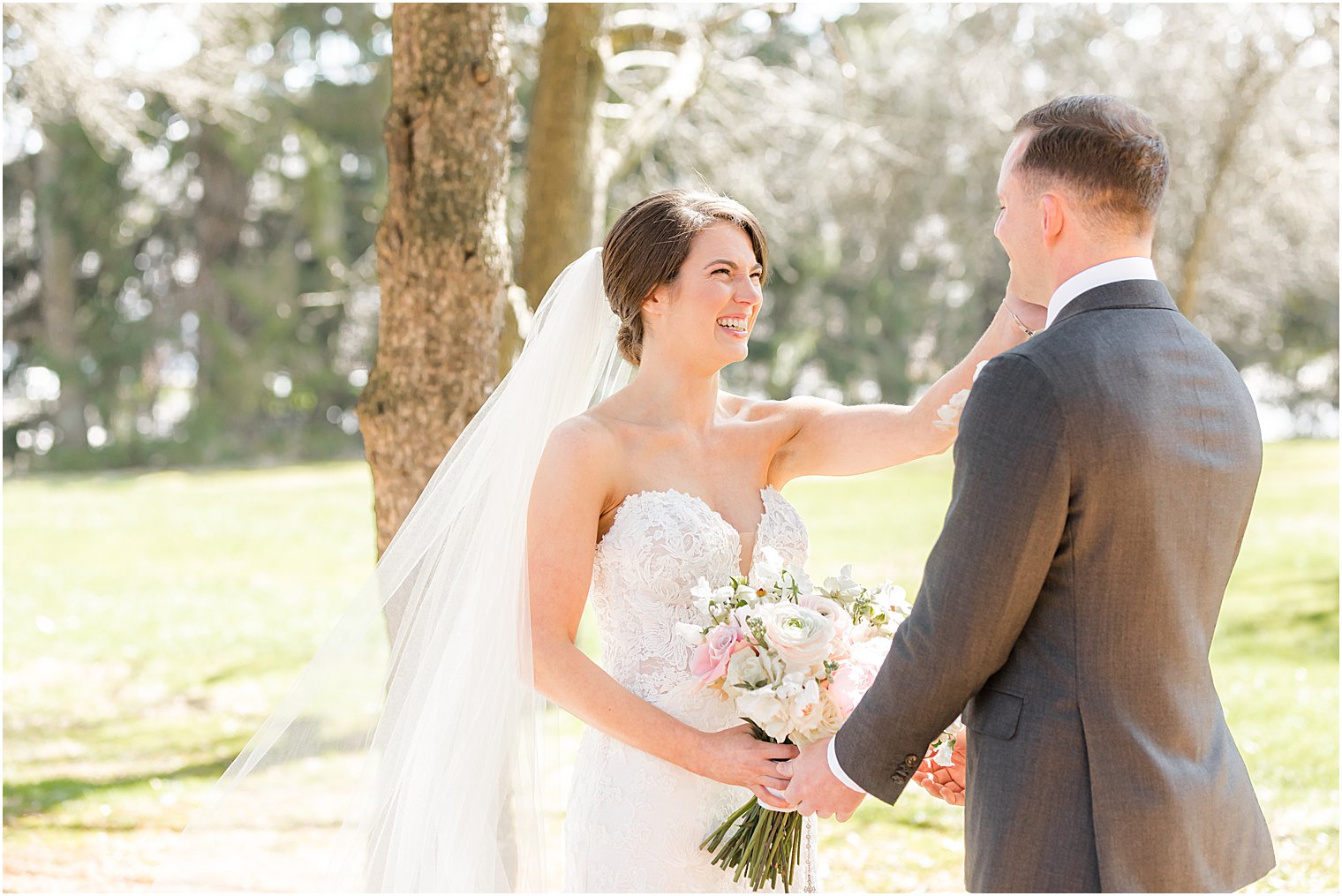 bride wipes away tears for groom during first look