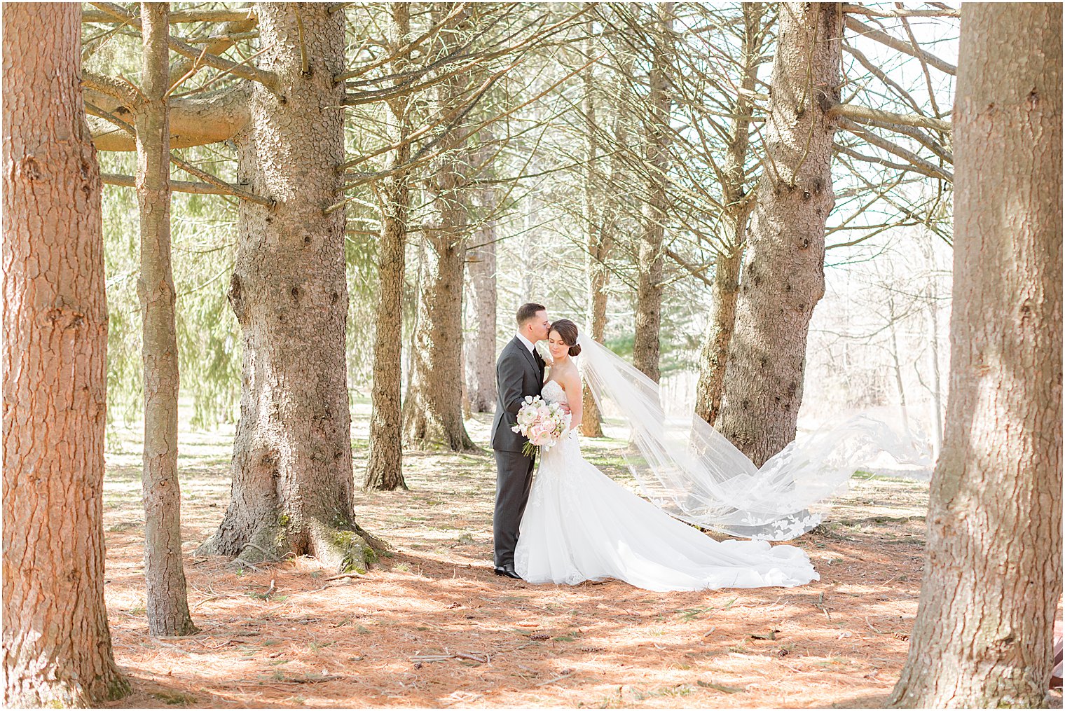 bride and groom kiss with bride's veil floating 